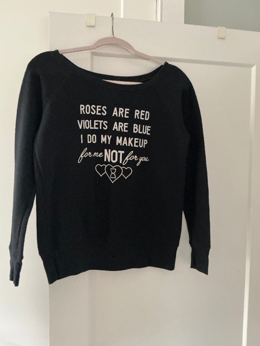 A black off-the-shoulder sweatshirt featuring the white graphic text